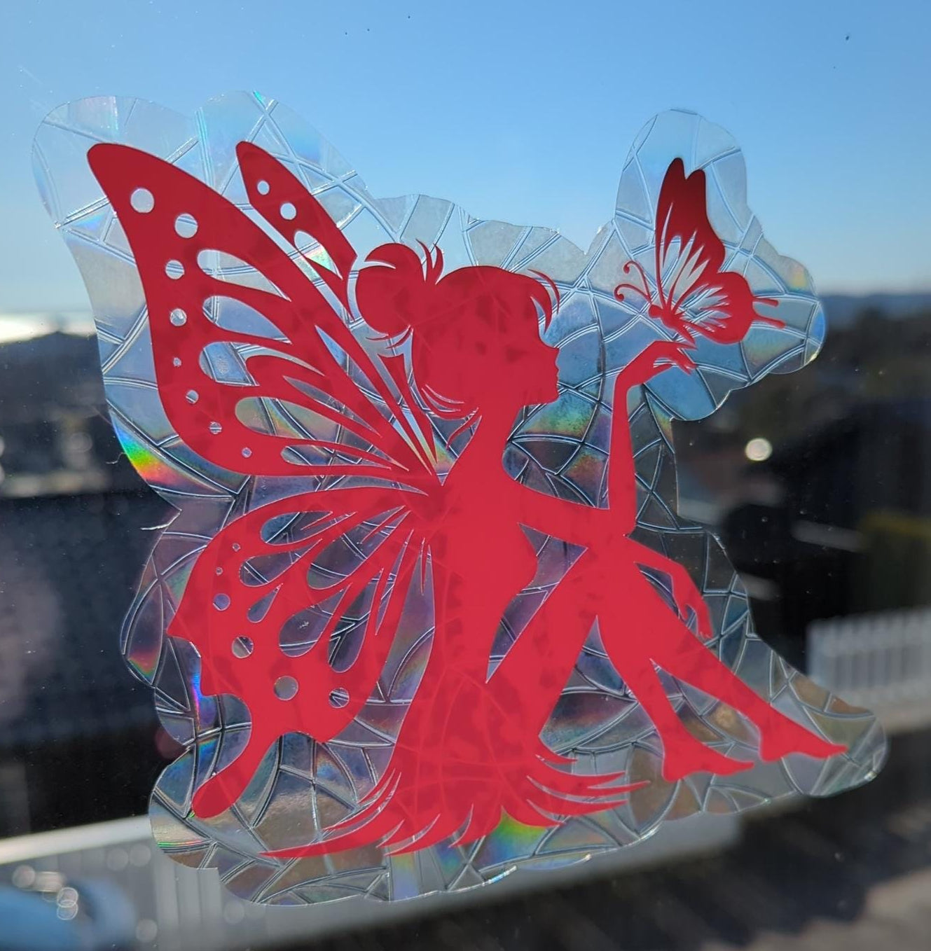 Pink fairy and butterfly window decal on a glass surface